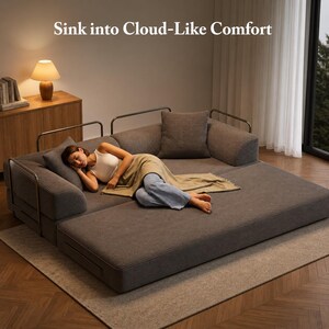 Puede incluir: Un sof&aacute; modular gris con una persona acostada sobre &eacute;l, cubierta con una manta. El sof&aacute; tiene una textura de pana y detalles met&aacute;licos. El texto "Sink into Cloud-Like Comfort" est&aacute; en la parte superior de la imagen. Una l&aacute;mpara y un armario de madera est&aacute;n en el fondo.