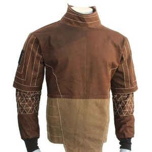 May include: A brown and tan long-sleeve shirt with a high collar and white topstitching. The upper chest and shoulders are dark brown, while the lower torso is a lighter tan. The sleeves feature a geometric white stitched pattern and black cuffs.