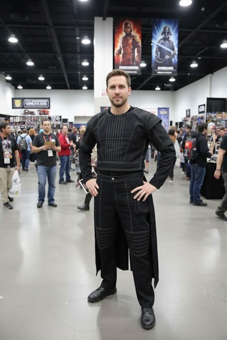 May include: A black long-sleeved top and matching trousers featuring white contrast stitching. The top has vertical line detailing on the chest, while the trousers include reinforced knee panels, a small side pocket, and a long back panel extension.