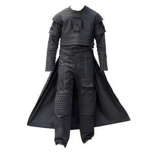 May include: A black outfit consisting of a short-sleeved top with a square chest emblem, long sleeves with vertical pinstripes, and trousers featuring quilted knee panels, a side cargo pocket, and a long, flowing back panel or cape attachment.