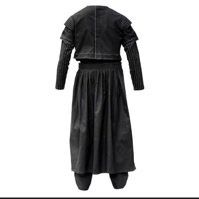 May include: A black ensemble consisting of a cropped jacket with structured shoulders and long sleeves featuring thin white pinstripes, paired with a high-waisted, floor-length pleated skirt. The garment is solid black with visible white stitching.