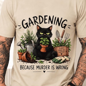 Peut inclure: Un t-shirt couleur sable avec une illustration d'un chat noir tenant une plante en pot. Le texte indique GARDENING BECAUSE MURDER IS WRONG. Autour du chat se trouvent des outils de jardinage, un arrosoir et une caisse en bois marquée PLANTS MAKE ME HAPPIER.