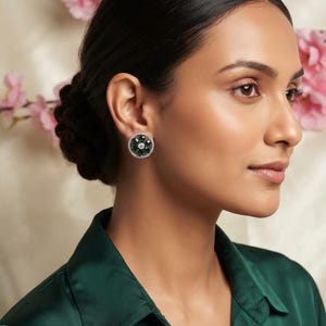 Peut inclure: Une boucle d'oreille à clou circulaire composée d'une pierre centrale transparente entourée de six pierres vert foncé taille marquise, le tout encadré par un bord de petites pierres pavées transparentes sur une base métallique.