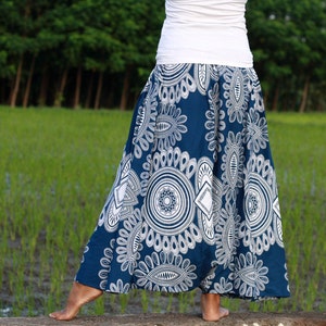May include: A long, flowing skirt in a deep blue hue, adorned with a white, intricate floral pattern. The skirt is paired with a simple white top. The design features a repeating motif of stylized flowers and geometric shapes, creating a bohemian aesthetic.
