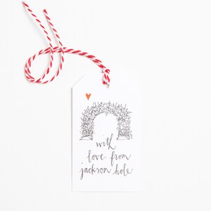 May include: White gift tag with a red heart and a black and white illustration of an archway. The text "with love from Jackson Hole" is written in black cursive.