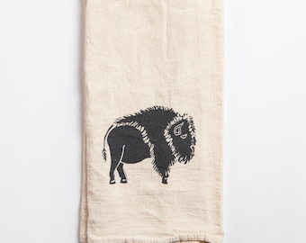 May include: A cream-colored kitchen towel with a black silhouette of a buffalo printed on it.