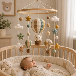 Peut inclure: Un mobile pour bébé en crochet composé d'une montgolfière centrale avec un petit ours dans la nacelle, entourée de nuages, d'étoiles et de ballons suspendus dans des tons doux de beige, vert sauge et jaune, fixés à un cadre en bois circulaire.