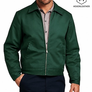 May include: A dark green zip-up jacket with a classic collar, long sleeves, and two front pockets. The jacket is worn over a light grey button-down shirt. The logo HEXONLEATHER with a hexagonal icon is visible in the upper right corner.