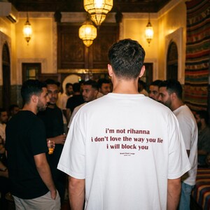 May include: A white short-sleeved t-shirt featuring dark red text on the back that reads: i'm not rihanna, i don't love the way you lie, i will block you. Below the text, smaller print reads: Brand Think Long, since 2024.