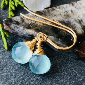 Peut inclure: Une paire de boucles d'oreilles en fil d'or avec des gouttes de chalcédoine bleu clair.