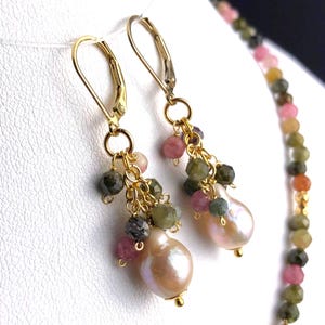 Può includere: Orecchini d'oro con un ciondolo di perla e un gruppo di pietre preziose rosa, verdi e nere.