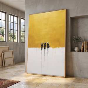 Könnte beinhalten: Großes abstraktes Gemälde mit goldenem Rahmen. Das Kunstwerk zeigt einen gelb-weißen Hintergrund mit drei schwarzen Figuren, die Hüte tragen. Schwarze Linien erstrecken sich von den Figuren nach unten.