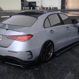 Può includere: Una berlina argentata con tetto nero e vetri oscurati è parcheggiata su una superficie di asfalto bagnato. L'auto ha uno spoiler, cerchi neri e una targa. L'auto è di design moderno.