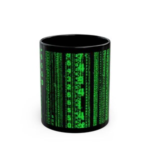 May include: Black coffee mug with a green digital rain pattern, resembling computer code. The mug has a shiny finish and a cylindrical form, ideal for hot drinks. The design is a repeating pattern of green numbers and symbols.