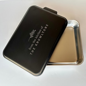 Może przedstawiać: Czarna forma do pieczenia z pokrywką. Pokrywka ma wygrawerowany napis "from the kitchen of THE KNOWLTONS".