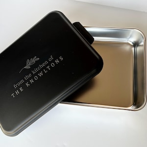 Może przedstawiać: Czarna forma do pieczenia z pokrywką. Pokrywka ma wygrawerowany napis "from the kitchen of THE KNOWLTONS".