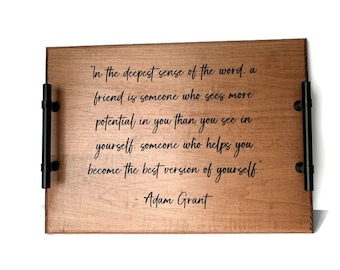 May include: A wooden serving tray with black metal handles. The tray has a quote engraved on it: "In the deepest sense of the word, a friend is someone who sees more potential in you than you see in yourself. Someone who helps you become the best version of yourself." - Adam Grant