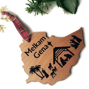 May include: Wooden Christmas ornament shaped like the country of Ethiopia with the words "Melkam Genna" and a nativity scene engraved on it.