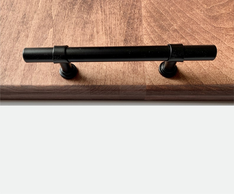 Close up of wooden serving tray edge, wood grain, and black steel handle.