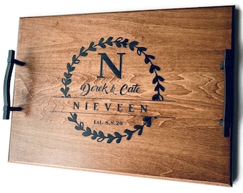 May include: A wooden serving tray with black handles. The tray is engraved with a wreath of leaves, the letter "N", the names "Derek & Cate", the word "NIEVEEN", and the text "Est. 8.8.20".