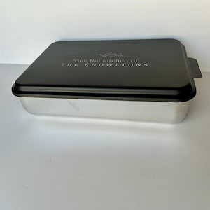 Może przedstawiać: Czarna metalowa forma do pieczenia z srebrnym wnętrzem i pokrywką. Na pokrywce znajduje się napis "From the kitchen of THE KNOWLTONS".