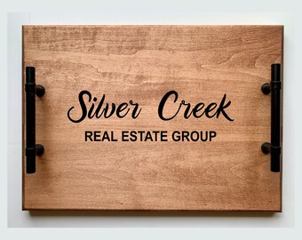 May include: A wooden serving tray with black metal handles. The tray has the text "Silver Creek Real Estate Group" engraved on it.