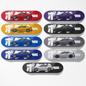 May include: A collection of ten skateboards, each featuring a different colored car design. The skateboards are in various colors, including red, purple, yellow, black, blue, and gray. Each board has Japanese text and a car graphic.