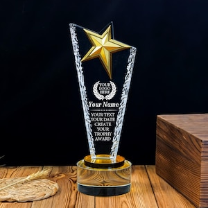 May include: A clear acrylic trophy featuring a gold star at the top and a circular base. The trophy includes etched text that reads: YOUR LOGO HERE, Your Name, YOUR TEXT, YOUR DATE, CREATE YOUR TROPHY AWARD. The edges have a textured, jagged design.