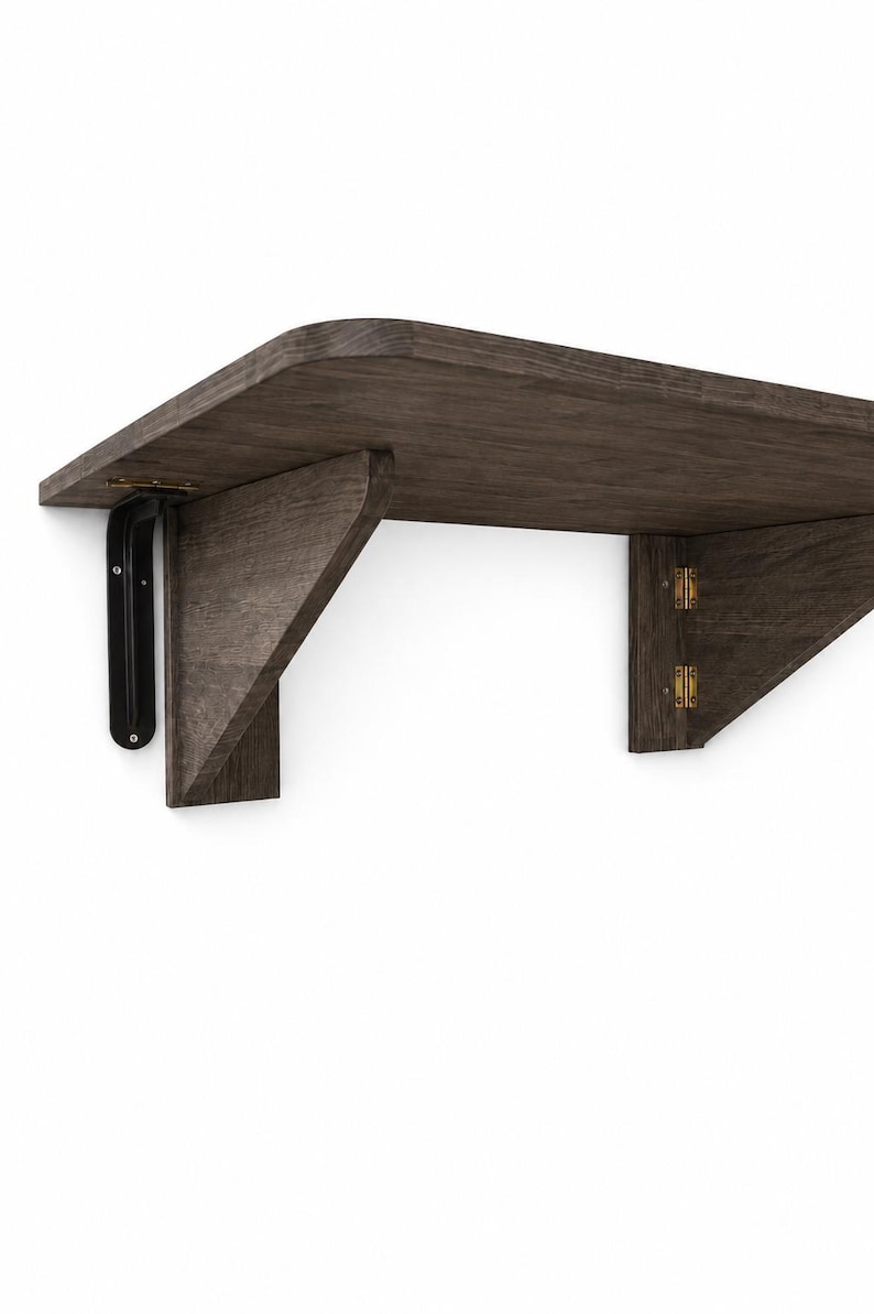 May include: A dark brown wooden wall-mounted folding shelf with a smooth, rounded front edge. The shelf features a black metal bracket on the left side and two gold-colored metal hinges connecting the triangular support piece to the main shelf board.