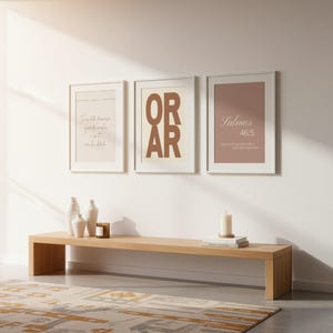 Pode incluir: Três quadros decorativos com molduras brancas. O quadro da esquerda tem texto bege, o central apresenta o texto castanho OR AR e o da direita exibe o texto branco Salmos 46:5 sobre um fundo rosa seco.