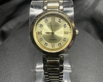 Reloj de cuarzo para mujer Ellen Tracy con esfera dorada, detalles de diamantes y brazalete de plata romana.