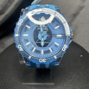 Pode incluir: Um relógio Invicta Subaqua azul claro com caixa e pulseira azul translúcida. O mostrador apresenta marcadores de hora brancos, ponteiros luminosos e o texto Invicta Subaqua Water Resistant. A luneta inclui os números brancos 20, 30, 40 e 50.
