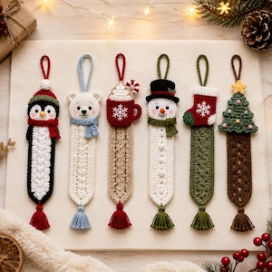 May include: Six crocheted bookmarks featuring holiday designs: a penguin in a hat, a polar bear with a scarf, a mug of cocoa, a snowman with a top hat, a red stocking, and a green Christmas tree, each with a matching yarn tassel at the bottom.