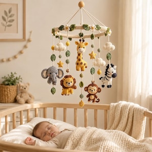 Könnte beinhalten: Ein hängendes Baby-Mobile mit gehäkelten Figuren von Giraffe, Elefant, Löwe, Affe und Zebra. Der kreisförmige Rahmen ist mit weißen Blüten und grünen Blättern verziert, ergänzt durch gehäkelte Wolken, gelbe Sterne und kleine bunte Kugeln.