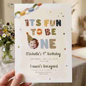 May include: A rectangular birthday invitation card featuring a paper chain graphic at the top and the text ITS FUN TO BE ONE with a photo of a child wearing a party hat. It includes the details Michelle's 1st Birthday, July 12, 2026, 7:00 PM, and location.