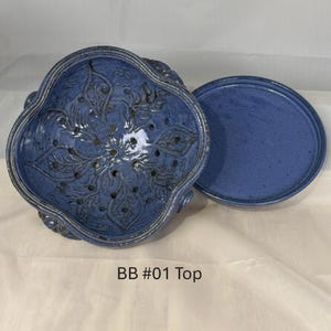 May include: A blue ceramic berry bowl with a scalloped rim and a matching flat blue saucer. The bowl features a carved leaf pattern and drainage holes throughout the base. The text BB #01 Top is printed below the ceramic pieces.