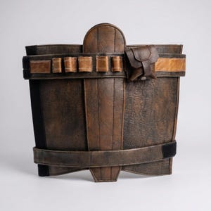 May include: A dark brown textured utility belt featuring a central vertical panel, two horizontal straps, and a series of small loops for storage. A small, square, dark brown pouch with a snap closure is attached to the upper strap.
