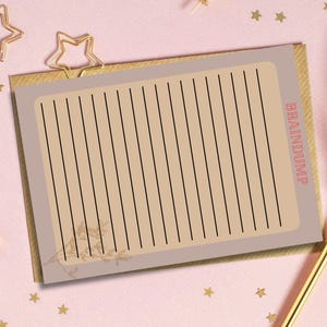 May include: A lined notepad with the text "BRAINDUMP" in red, featuring a beige paper with black lines and a floral design. The notepad is on a pink surface with gold star-shaped confetti and a gold pen.