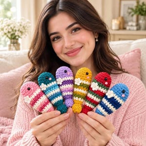 May include: A set of six small, crocheted fish toys, each featuring horizontal stripes in various color combinations including pink, teal, purple, yellow, red, and blue, with a small white flower accent and black bead eyes.