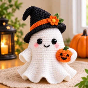May include: A white crocheted ghost figurine wearing a black witch hat with an orange band and a small orange flower. The ghost has black safety eyes, a stitched smile, pink cheeks, and is holding a small orange crocheted jack-o'-lantern.