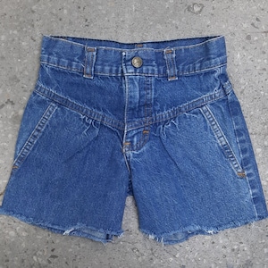 Puede incluir: Shorts vaqueros azules con cintura alta y un dise&ntilde;o de costura angular &uacute;nico. Los shorts tienen cierre de bot&oacute;n y bordes deshilachados en el dobladillo. Un estilo cl&aacute;sico e informal.
