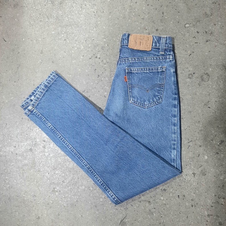 Puede incluir: Vaqueros de mezclilla azul claro con un dise&ntilde;o cl&aacute;sico de cinco bolsillos. Los vaqueros tienen un corte de pierna recta y una peque&ntilde;a etiqueta naranja en el bolsillo trasero. Los vaqueros tienen un parche de cuero en la cintura.