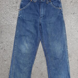 May include: A pair of blue denim jeans with a classic five-pocket design. The jeans have a button and zipper closure, belt loops, and copper rivets. The denim has a faded appearance, suggesting wear. The jeans are likely for children.