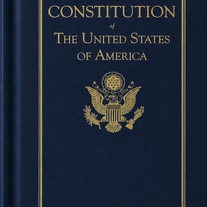 May include: A dark blue hardcover book titled The Constitution of The United States of America in gold lettering. The cover features a gold embossed Great Seal of the United States, depicting an eagle with a shield, centered below the title text.