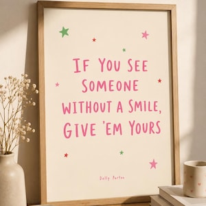 May include: A framed wall art print featuring the pink text IF YOU SEE SOMEONE WITHOUT A SMILE, GIVE 'EM YOURS and the name Dolly Parton. The cream-colored background is decorated with small green, red, and pink stars in a simple font.