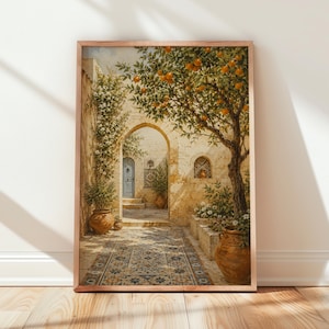 May include: A framed wall art print depicting a Mediterranean courtyard scene with a stone archway, a blue door, and a large orange tree. The ground features a patterned tile floor, and terracotta pots are placed near the stone walls and greenery.