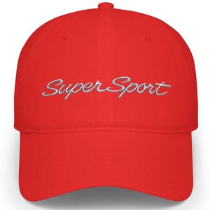 Op de afbeelding: Een felrode baseballcap met een gebogen klep. De cap heeft de tekst "Super Sport" in lichtblauwe letters geborduurd. De cap is gemaakt van een zacht materiaal.