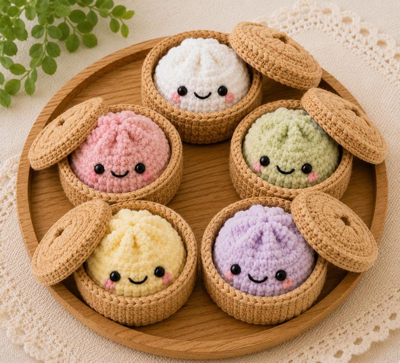 May include: Five crocheted plush dumplings in various pastel colors including white, pink, light green, yellow, and lavender. Each dumpling features a smiling face with black eyes and pink cheeks, nestled inside a small tan crocheted steamer basket.