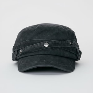 May include: A black military-style cap with a short brim. The cap features a wraparound strap secured with silver-colored metal buttons. The fabric appears to be a worn, textured material. The cap is set against a plain white background.