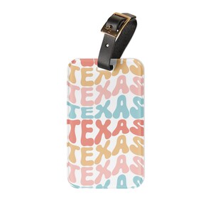 Könnte beinhalten: Ein rechteckiges Kofferanhänger-Etikett mit einem sich wiederholenden Muster des Wortes TEXAS in wellenförmiger Bubble-Schrift. Der Text erscheint in abwechselnden Reihen in gedecktem Gelb, zartem Rosa und Hellblau. Ein schwarzer Lederriemen mit goldener Schnalle.